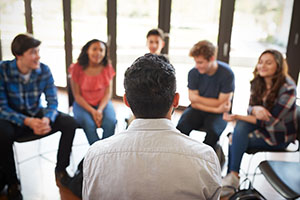 group of people sitting in chairs in a circle talking