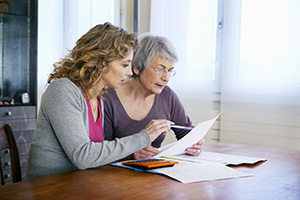 Two women sitting at a table looking at a peice of paper